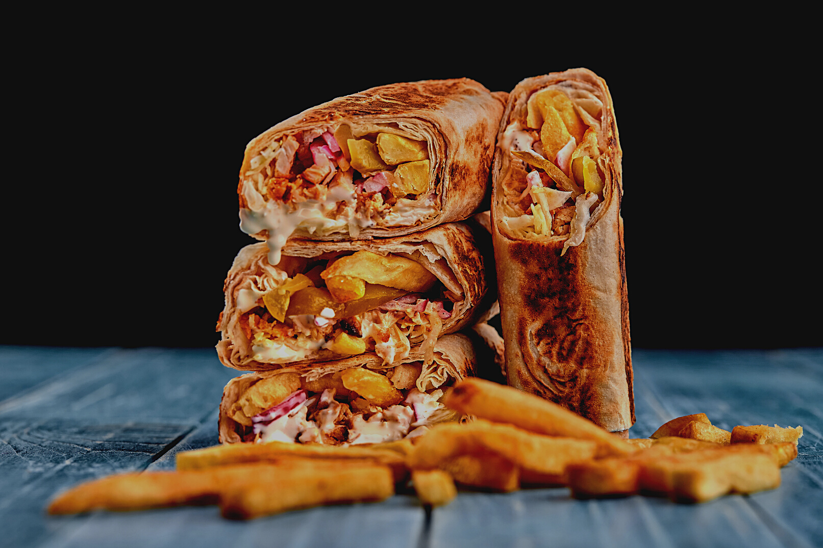 Shawarma Chicken Roll in a Pita with Fresh Vegetables, Cream Sauce and French Fries on Wooden Background. Selective Focus